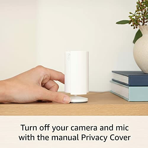 Hand adjusting privacy cover on a security camera on a table.